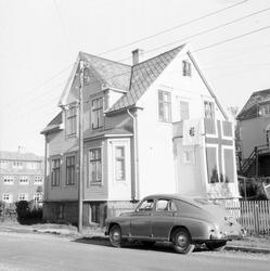 "Sanitetshuset" prydet med flagg. Bil i forgrunnen.