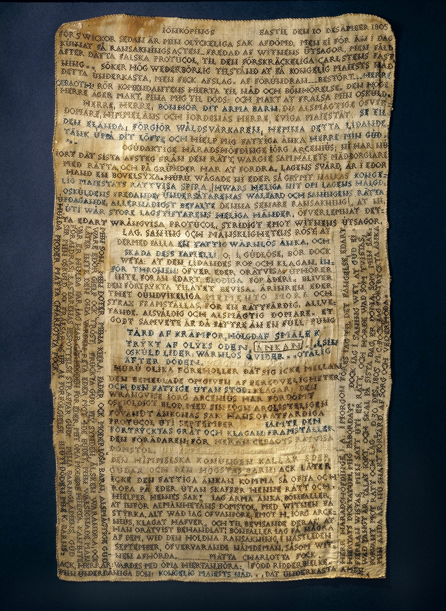 Lång text broderad i korssöm i svart, blått och vitt tunt lingarn på ofärgat tuskaftat linne, sammansytt av 27 små tygbitar. Väven har 25 tr/cm och 24 insl/cm. Rullfåll med svart tråd. Texten är en klagoskrift och en vädjan om nåd från Mätta Charlotta Fock f. Ridderbielke daterad Jönköpings bastil den 10 däsember 1805.
"Ridderbielke, Metta Charlotta, gift med sergeanten Henrik Johan Fock, förgjorde 1802 sin man jemte tvänne sina barn genom gift, för att få gifta sig med sin amant, gifte skogvaktaren, sedermera roteringskarlen, Johan Fägercrantz, sedan Lilja kallad, som dömdes till 28 dygns vatten och bröd. Efter flera års sittande på bekännelse å Carlstens fästning, blef hon slutligen dömd att mista högra handen, halshuggas och å båle brännas, hvilket allt försiggick d. 7 Nov, 1810 å Fägredsmon i Westergöthland."
Ur Anteckningar om svenska kvinnor utg. 1864 av P.G. Berg.
Hennes skuld kunde aldrig bevisas och klagoskriften är  en nådeansökan för den orättvisa rättegång och dom som hon menar sig ha fått. 
Hela texten i broderiet.  se under Information.
Anm. Broderiet urtaget ur sin glasade ram.
/Berit Eldvik 2011-12-29