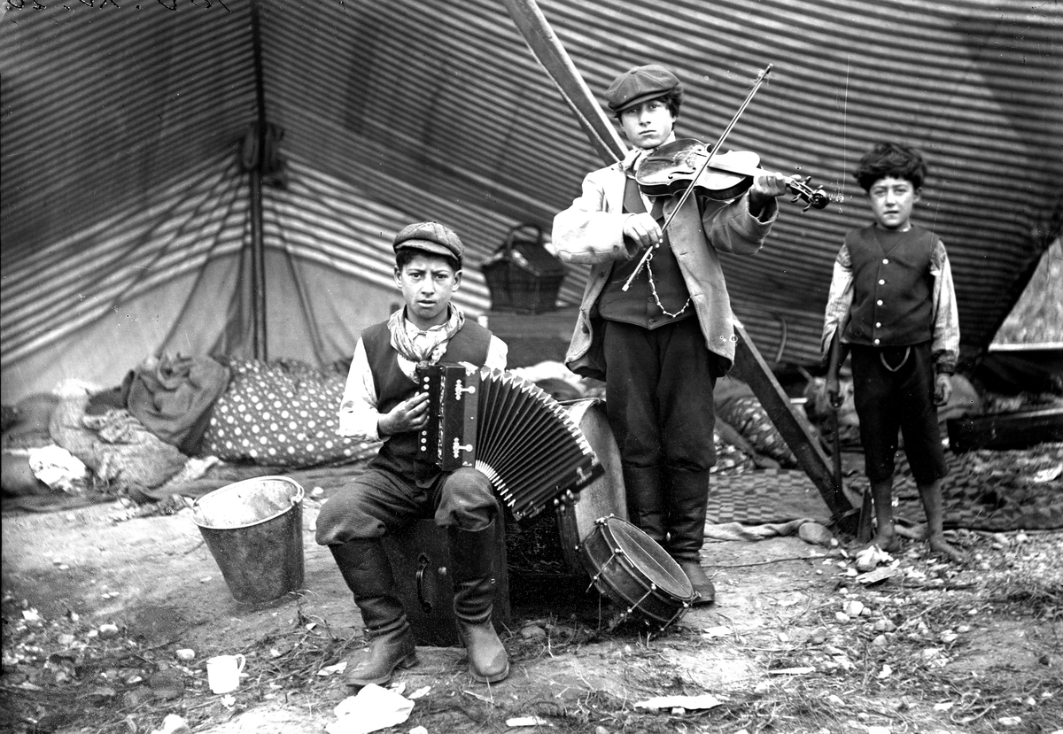 Romska barn, musikanter. 1900-1910. Romsk familj, fotograferade av P A Wassberg 1900-1910, då slagit läger vid skärningen av Arbogatullen-Bergslagsvägen. Bilderna sorterades under beteckningen "Zigenare- typer".