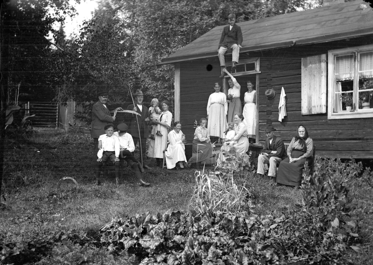 Släkten samlad en sommarsöndag vid Åsmundshyttan nr. 9 "Erik-Anders" fäbodstuga. Det är Anna Hansson som bjudit sina syskon Lotten och Axel med familjer.
På taket Joel Hansson f. 22 augusti 1903, d. 17 november 1975. Bakre raden från vänster Per Jönsson f. 2 december 1870, d. 8 juni 1935, Axel Jönsson f. 23 mars 1883, d. 7 september 1963, Bengt Jönsson f. 6 mars 1919, d. 25 juni 1973, Lydia Jönsson f. 21 februari 1891, d. 13 juni 1976, Anna Greta Westlund, Maria Jönsson f. 5 mars 1888, d. 20 januari 1980, Anna Lind f. 3 juni 1890. Främre raden från vänster Valle Jönsson f. 30 oktober 1913, Anselm Jönsson f. 18 augusti 1910, Olga Jönsson f. 24 januari 1891, d. 24 maj 1927, Anna Hansson f. 9 april 1876, d. 3 december 1949, Greta Jönsson f. 13 september 1919, Lotten Jönsson f. 6 januari 1881, d. 3 januari 1963, Per Hansson f. 5 januari 1864, d. 14 november 1929 och Brita Andersdotter.