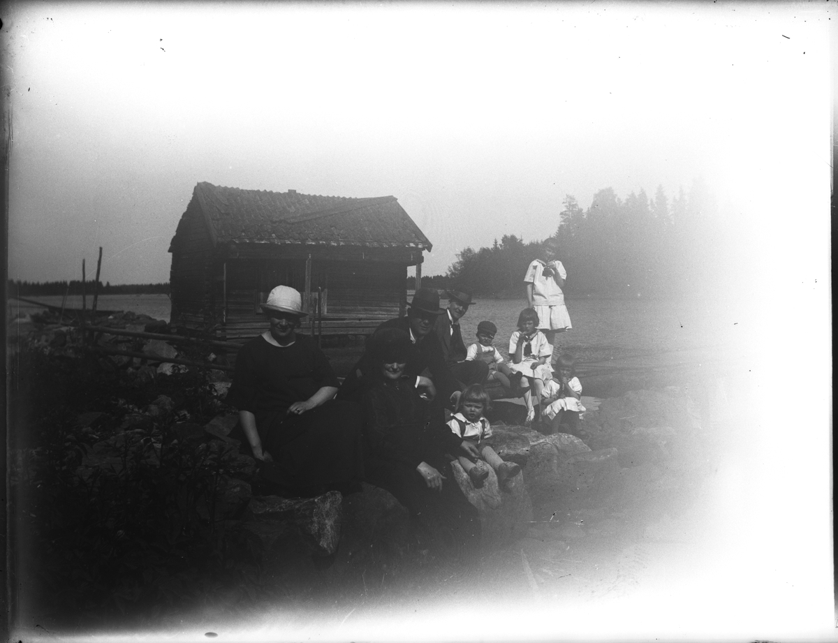 Troligen i Sikvik. Längst till vänster Ellen Olsson, en svägerska till Elna Brundin, därefter Anna Larsdotter Olsson (Elnas mor) och bakom henne David Brundin. Sören Brudin sitter tillsammans med mormodern Anna. Övriga barn Brundin i bakgrunden tillsammans med Einar Olsson och hans son Bengt. Bilden kan var från 1923-24.