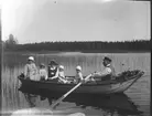 En roddtur, troligtvis på Lingan utanför Lingbo. Elna Brundin med vidbrättad hatt sitter med sina döttrar Karin och Ingrid. Mannen som ror okänd.