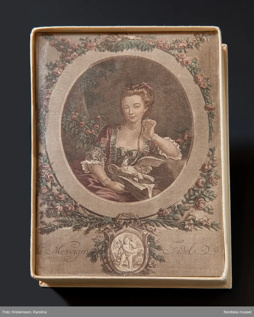 Huvudliggaren:
"Konfektask, kartong, rekt., trycklock; på locket bröstbild av dam och Amor; 'Le Messager Fidel'. Gåva 20/11 1933 av fröken Dagmar Landelius, Stockholm."

Bilaga:
"En samling föremål från Landelius Kungl. hovkonditori, Storkyrkobrinken 9, Stockholm, skänkta av fröken Dagmar Landelius. Givarinnans morfar, J. C. Landelius, öppnade 1858 affären på Storkyrkobrinken. På 1860-talet öppnade samma firma den s.k. paviljongen på Drottningholm, vilken ombyggdes 1903. Affärsrörelsen på Storkyrkobrinken drevs till 1910, då huset skulle rivas, varför huvudaffären flyttades till Strandvägen 7A samt en filial till 16 Storkyrkobrinken.
I den gamla affären skyltades med två speldosor (nr 194.909 och 194.921), samt en hare, som spelade på trumma, och en docka (194.921), vilken kläddes i olika dräkter efter årstiderna och samma docka hade även en sorgdräkt från 1870-talet, vilken användes vid kungssorg.
Slottet gjorde alla sina beställningar hos Landelius. Den 24 januari var det oftast bjudning med minst 1 000 karameller beställda. Drottning Sophia beställde Jesusbarn med gloria till småprinsessornas julgran samt tomtar och dylikt. Senare flyttade kronprinsparet över sina beställningar till annan firma, men de övriga kungliga gjorde fortfarande sina inköp hos Landelius, liksom flera andra större restauranger.
I det s.k. 'änglaskåpet' i affären på Storkyrkobrinken förvarades små figurer av dragant förfärdigade av fröken Beda Pegel, Karlavägen. Hon gjorde stora figurer till krokaner, begravningsföremål såsom biblar, kors och lamm etc. och till flyttgröt, tomtar med grötfat, samt till barndop lindebarn burna av storkar.
Från Paris tog man hem diverse små prydnadssaker till karameller. Firman Lumarier hade små verkstäder för olika material; vax, metall och bensaker allt utfört för hand. Små soffor och biljarder av ben lades som överraskningar i påskäggen.
Alla karameller inlades i affären och pryddes på olika sätt: svanen lades på en spegel med gräskant osv. Även efterrätter beställdes och om man t.ex. önskade ett lapplandskap gjordes kåtan av bakverk med snöbollar av spunnet socker medan renen och lapparna voro skurna i trä och återtogs dagen därpå. Denna efterrätt var synnerligen omtyckt på 1890-talets början."