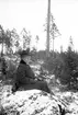 Sitter i skogen. Tidsomfånget är 1900 - 1940