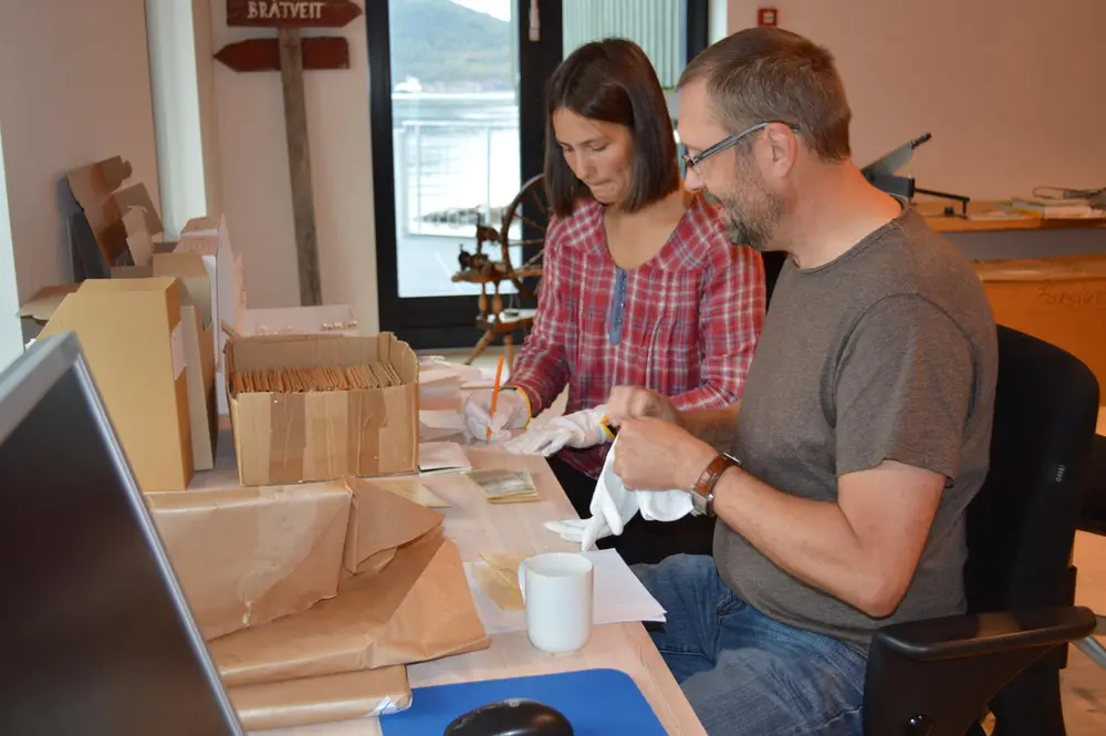 Bildet viser to museumsmedarbeidere som jobber med arkivmateriale