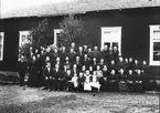 Skollärare Åström i Stråtjära i kretsen av sin familj, han sitter i första raden (stort skägg), med hustru och 9 barn. Bakom honom tre lärare i Skog. Troligen någon bemärkelsedag.