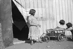 Tre barn leker med en vagn/skrinda. Familjen Taikons läger i Johanneshov, södra Stockholm.