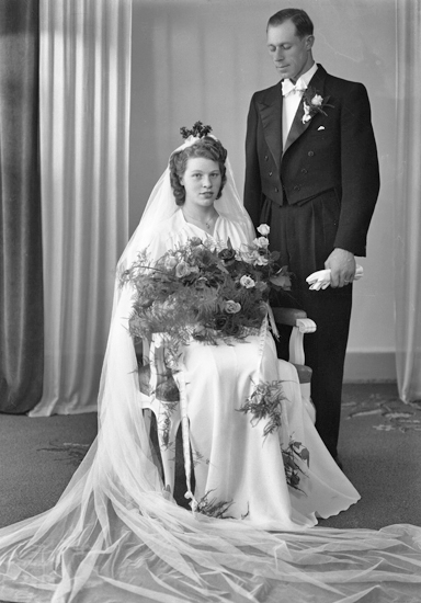 Foto av ett brudpar. Hon är klädd i vit brudklänning med slöja och myrtenkrona. Han bär frack.
Helfigur. Ateljéfoto.
Kan ev. vara: Karl Gunnar Larsson (1920-1978), Alvesta. Gift 23 juni 1942 med Iris Majken Elise (1920-1998).
Källa: Sveriges Dödbok 1901-2009.