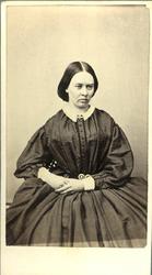 Porträtt (knäbild, halvprofil) av en sittande kvinna i mörk 