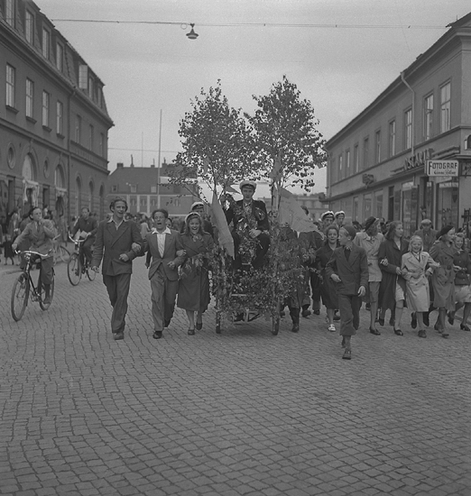 Studenterna, 28/5 1945. 
En student körs i lövad kärra längs Storgatan, av glada kamrater. I bakgrunden syns Stortorget m.m.

Vad gäller avgångsklasserna 1945 - Se "Lärare och Studenter vid
Växjö Högre Allmänna Läroverk 1850-1950" (1951), s. 177-180.