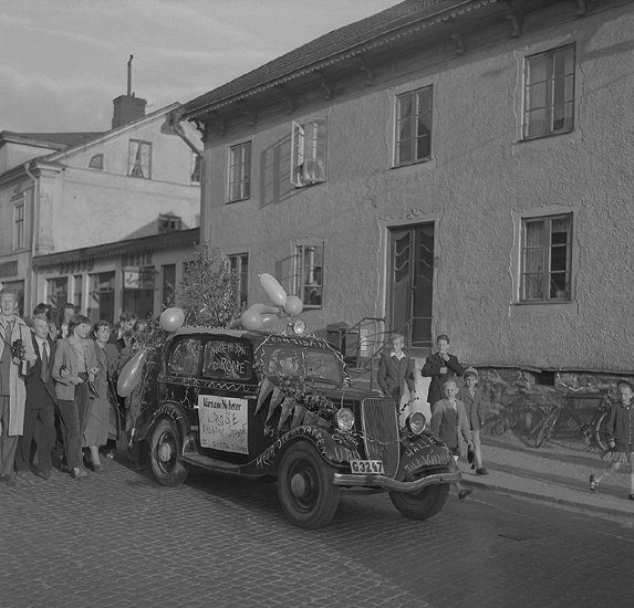 Studenterna första dagen, 1950.
En student körs hem utmed Storgatan i  lövad och dekorerad bil, där
man bl a kan läsa "Värnamo Nyheter", "Lasse" m.m.

Angående avgångsklasserna 1950 - se "Lärare och Studenter vid Växjö 
Högre Allmänna Läroverk 1850-1950" (1951), s. 193-196, 289.