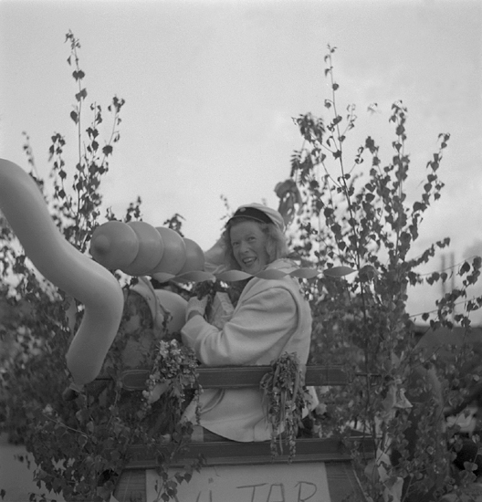 Studenterna första dagen, 1950.
En glad kvinnlig student, omgiven av lövruskor och ballonger.

Angående avgångsklasserna 1950 - se "Lärare och Studenter vid Växjö 
Högre Allmänna Läroverk 1850-1950" (1951), s. 193-196, 289.
