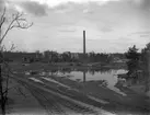 Järnvägsspår vid sjö och industrianläggning.