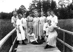 Tio flickor samlade på en träbro eller träbrygga.
