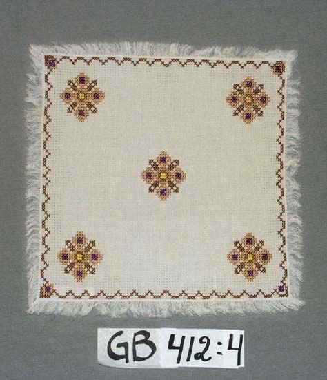 Duk. Broderad.
Mått:
300 x 310 mm + frans 20 mm.
Motiv:
Brunt, beige, lila och gult broderi. Fem stjärnor samt 
zick-zackbård i kanten. Ytterkanten langetterad.
Inskrivet i huvudkatalogen 1996-1997.
Funktion: Prydnadsduk, småduk