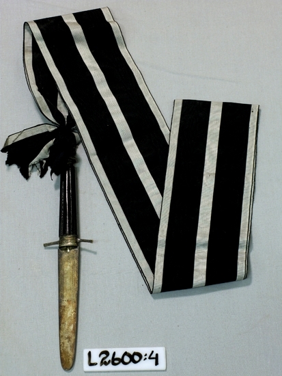 Metallkniv i 100 mm brett ripsband(silver-svart-silver-svart-silver)
Frimurarorden.

Inskriven i huvudboken 1933
Funktion: Ordenstecken inom Frimurarorden