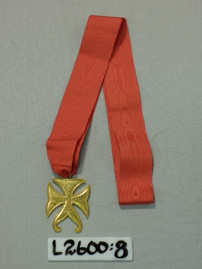 Ett 35 mm brett klarrött ripsband med förgylld variant av 
malteserkors (metall).
Text: "IBMBADIC."

Inskrivet i huvudboken 1933
Funktion: Ordenstecken (inom Frimurarorden ?)