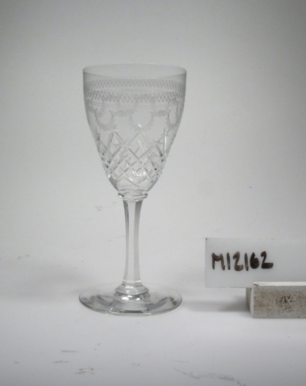 Glas (R.417).
Beskrivning: Slipad dekor i form av skär-rutor och facettben. 
Pantograferad bård.
Färg: Ofärgat klarglas.
Mått: Ovan angivna diameter avser glasets fotdiameter.
Inskrivet i huvudkatalogen 1942.
Funktion: Glas