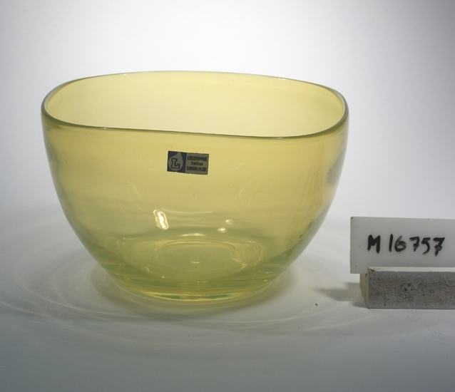 Skål.
Formgiven av Gunnar Ander.
Fyrkantig med avrundade hörn.
Urangul, svagt opatin.
Ovan angivna mått avser övre diameter.
Bottendiameter: 67 mm.
Blå etikett med "L" inom glasblåsa samt text. 
Se "Signering, märkning" ovan.
Inskrivet i huvudkatalogen 1959.
Funktion: Skål