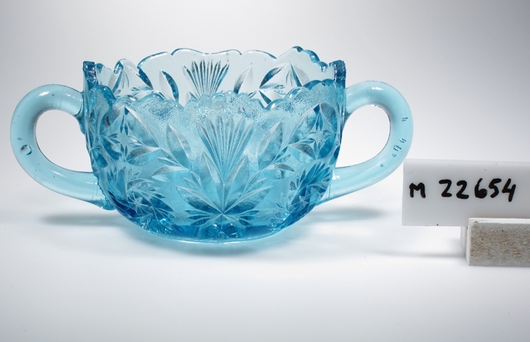 Sockerskål ur serien "Rosa".
Tillverkad på Sölvesborg, Sölvehyttan.
Beskrivning: Uddformad kant med stora tillverkningsfel. Två grepar. Imiterad skärslipning. Stjärna med kvast och bladrankor, samt två rosetter på varje sida. Stjärna i botten.
Färg: Ljust blågrönt glas, tämligen klart.
Mått: Ovan angivna diameter avser skålens övre diameter. 
Bottendiameter: 58 mm.
Inskrivet i huvudkatalogen 1974.
Funktion: Sockerskål