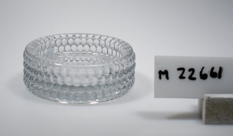 Ljusstake II (skålform).
Tillverkad på Sölvesborg, Sölvehyttan.
Beskrivning: Cylindrisk. Fyra rader av kulor i reliefform.
Färg: Ofärgat klarglas.
Inskrivet i huvudkatalogen 1974.
Funktion: Ljusstake