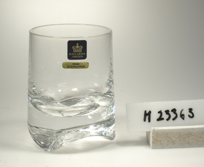 Tumlare. Tillverkat av Krona Bruken, Åseda glasbruk.
Formgivare: Bo Borgström.
Beskrivning: Konad (smalnar upptill). Tjock botten med tre uddar.
Färg: Ofärgat klarglas.
Kristallglas?
Mått: Ovan angivna mått avser övre diameter.
Bottendiameter: 70 mm.
Fyrkantig, svart etikett med krona och guldtext: Se "Signering, märkning" 1 ovan.
Avlång guldetikett med text: Se "Signering, märkning" 2 ovan.
Inskrivet i huvudkatalogen 1975.

Ur "Glas 75" utställningsglas.
Funktion: Tumlare
