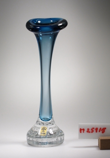 Hundbensformad vas, med luft i foten.
Blått underfång.
Etikett i guld med blå text: Åseda Sweden.
Funktion: Blomvas