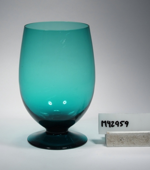 Ölglas, (tolkat av storlek och form, registerkortet benämner det "Goblet").
Smaragdgrönt ölglas på fot (utan ben).
På en lapp står: 1141/12 oz.

Enligt reg.kort: "Ej identifierat i katalog från Gullaskruf eller Älghult. Identifieringen baserad på uppgifter från Älghults glasbruk".
Funktion: Att dricka öl ur