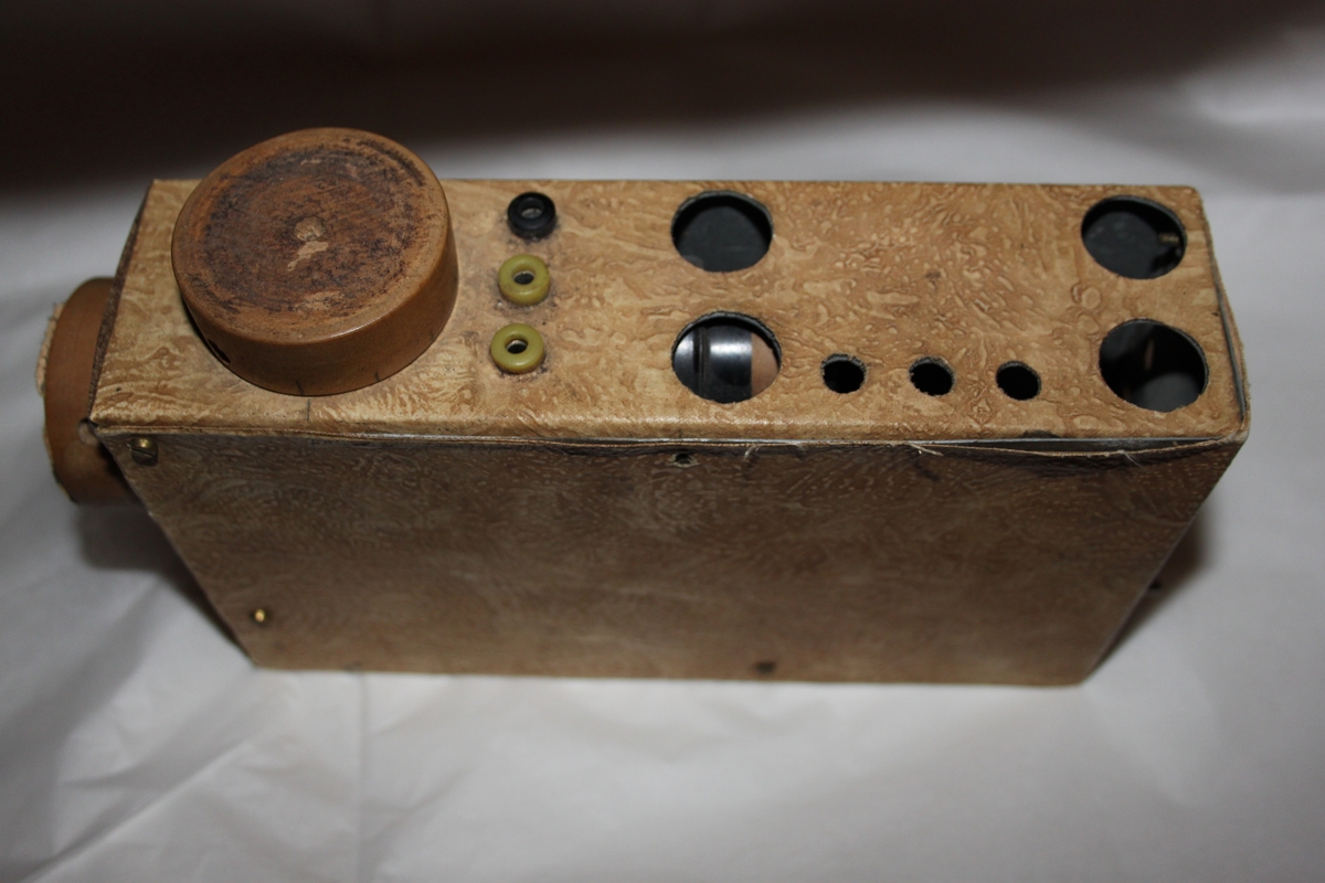 Radiomottaker, hjemmelaget. Rektangulært chassi laget i trefiner.. Med sorte høretelefoner med stempel OMEGA. Dette eksemplaret er fortsatt i utmerket stand. Det følger også med en improvisert antenne.