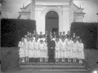 Gruppfoto av konfirmander med kyrkoherde Henrik Lindberg från början av 1900-talet.
