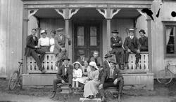 Gruppfoto i trappan av huset och verandan, från 1920-talet.

