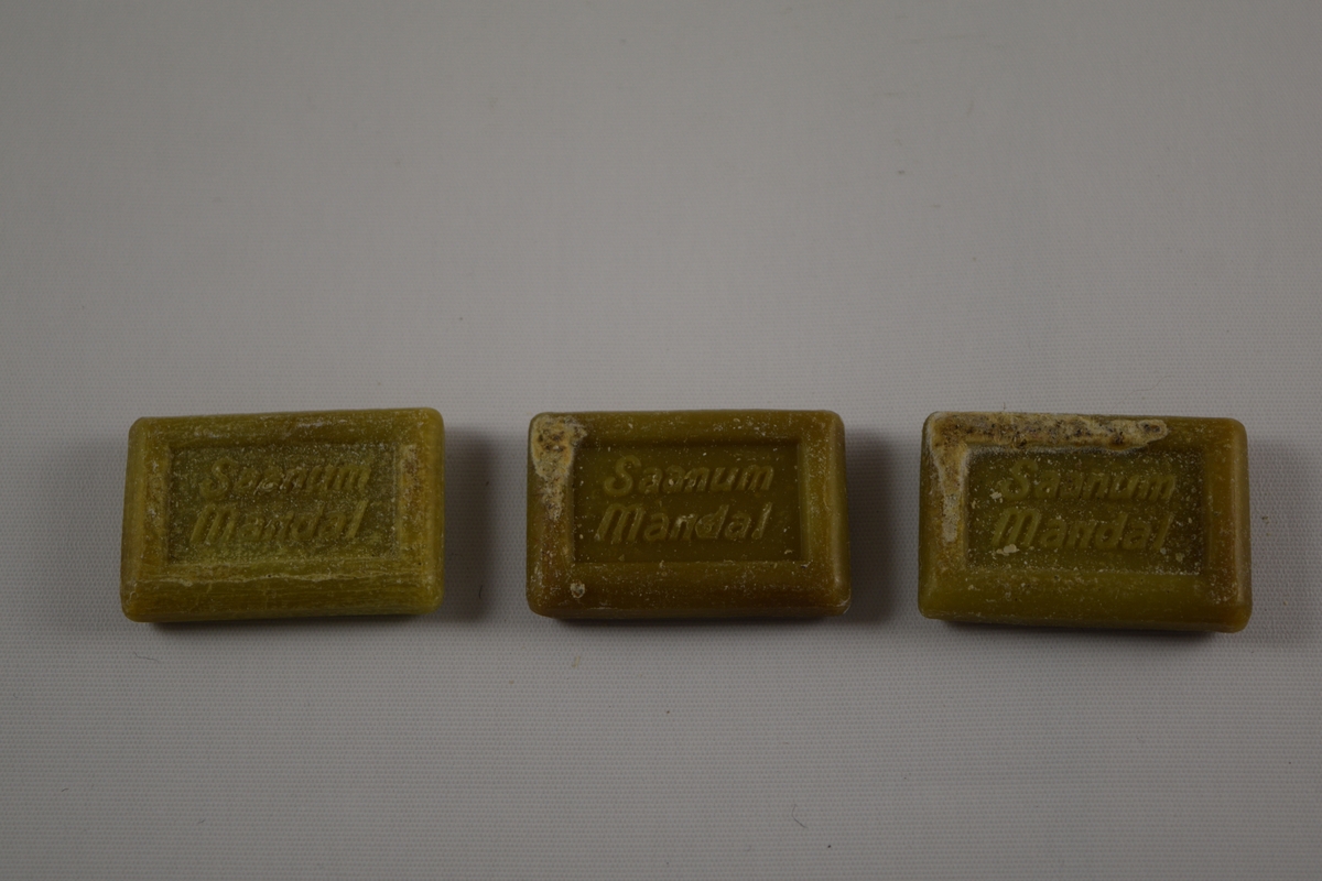 Rektangulær såpe, grønn, tre like såper (A, B, C) produsert på Saanums Sepefabrikk i Mandal. Rektangulær fordypning med relieffteksten "God morgen!" på overside og "Saanum Mandal" på underside.
