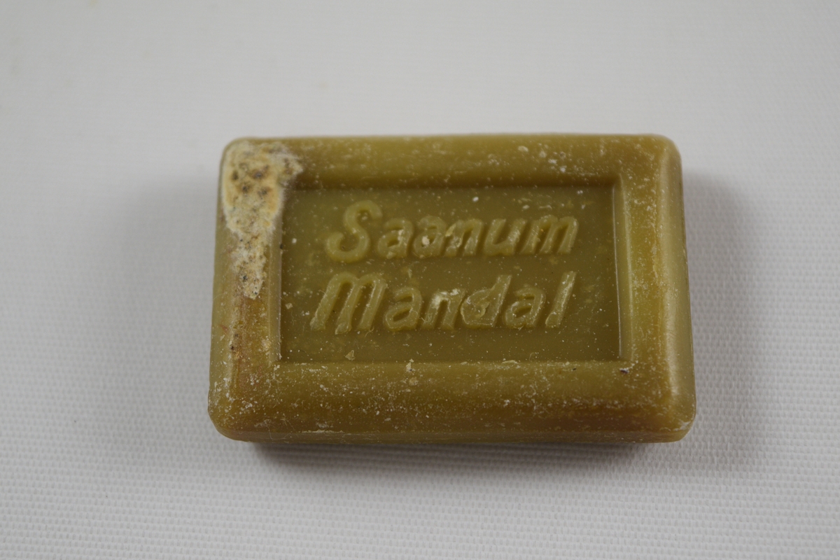 Rektangulær såpe, grønn, tre like såper (A, B, C) produsert på Saanums Sepefabrikk i Mandal. Rektangulær fordypning med relieffteksten "God morgen!" på overside og "Saanum Mandal" på underside.