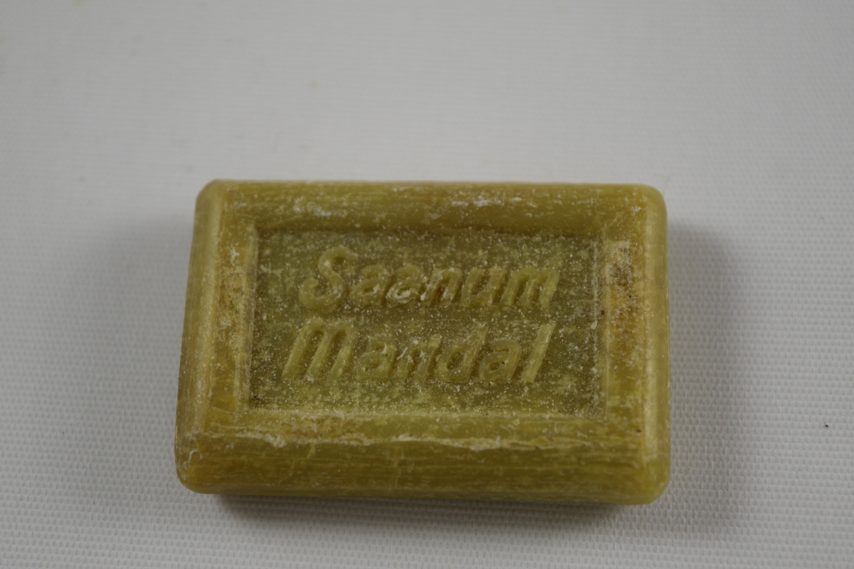 Rektangulær såpe, grønn, tre like såper (A, B, C) produsert på Saanums Sepefabrikk i Mandal. Rektangulær fordypning med relieffteksten "God morgen!" på overside og "Saanum Mandal" på underside.