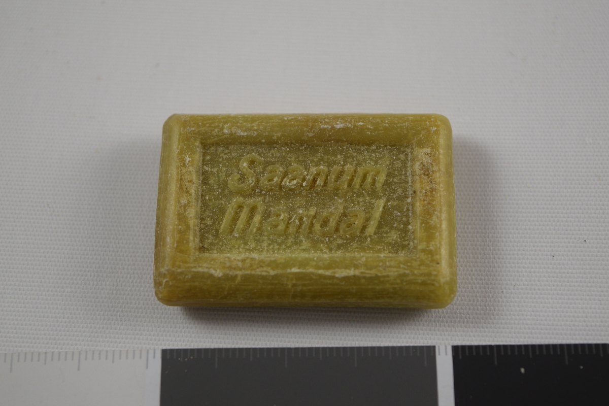 Rektangulær såpe, grønn, tre like såper (A, B, C) produsert på Saanums Sepefabrikk i Mandal. Rektangulær fordypning med relieffteksten "God morgen!" på overside og "Saanum Mandal" på underside.