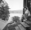 Kvinnan sitter på trappan till sommarstugan