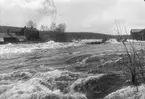 Vårfloden år 1916. Lenningeforsen med smedjan till vänster, skäkten och linspinneriet till höger.