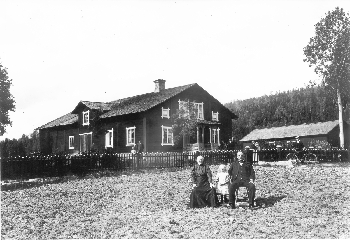 "Gammelnyströms" i Finnfara utanför Bollnäs. Bilden är tagen 1908 samma år som Sigrid Olsdotter dog. Flickan på bilden är barnbarnet Signe f 1904. Till höger maken Olof Nyström 1844-1928. Vid staketet Signes mamma Elin med sonen Olof f 1907. Vid cykeln Per Nyström 1880-1960.