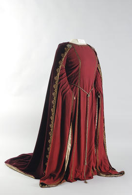 Kostume Kirsten Flagstad in the role of Isolde in Tristan and Isolde. A red dress with gold details in a mediavel style. A red velvet cape and a gold belt around the waist.