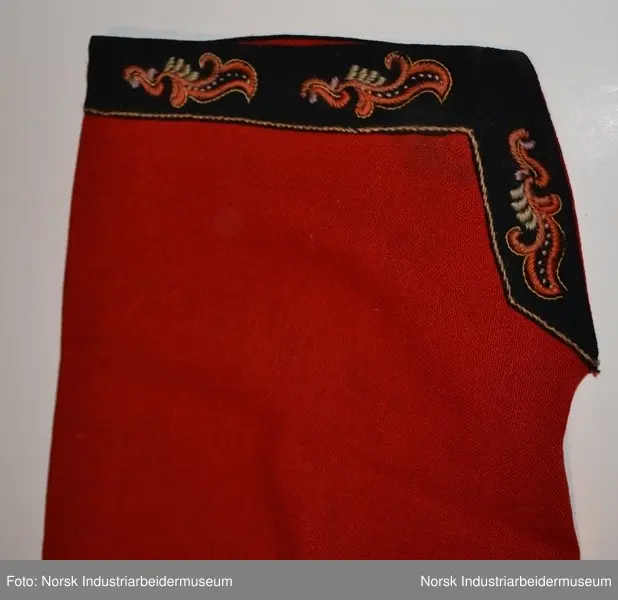 Rød tøye til Anne Bamle-bunad. Gul kanting sydd fast nederst på trøya. Kanten langs åpningsfolden og deler av halsen er svart og brodert med plattsøm. Svart kant med plattsøm-broderi. Bak på trøya er det en illudert klokke(folder) i ryggen og klipte taggekanter. Halsen på trøya er buet, noe som var vanlig på de tidlige bunadene Anne Bamle lagde. Trøya er ellers brodert med plattsøm på forsiden. 

Trøya (ikke ermene) er foret med et tynt, beige silke-/bomullstoff. Trøya har trekvartlange ermer.