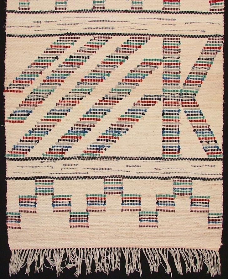 Matta, trasväv, 215 x 65. Vit bomullsvarp. Väften vita trasor, för de smala mellanränderna svarta. Mönstringen, delvis figurer i trasor i rött, rosa, grönt, blått, brunt och svart, livliga färger. Fransad. Våd till täcke. Ovansjö.

Äldre katalogisering av Elisabeth Thorman (enl. uppgift).

Utställd på Nordiska museet 1957-58.
Utställd 1980 "MATTOR" Forsbacka herrgård.
