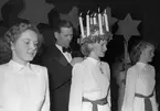 Mary Forslund, Gävle Lucia 1949. Hon är 21 år och handhar arkivet hos A/B Carl Larssons fotografiska atelier Tärnorna är Margareta Svensson, Harriet Jansson, Ulla Persson och Marianne Lundin. Luciatåget startar från Brandstation och går Nygatan - N. Skeppargatan - Drottninggatan - Stora Esplanadgatan och åter till Brandstationen. Soaré på teatern som arrangerat av köpmanna- och hantverkarungdomen i Gävle, leds av Macce Kjellin, kröntes Lucian med smycket av direktör Gösta Nygren, Furuvik. Lucia tävlingen arrangerades av Norrlands-Posten.