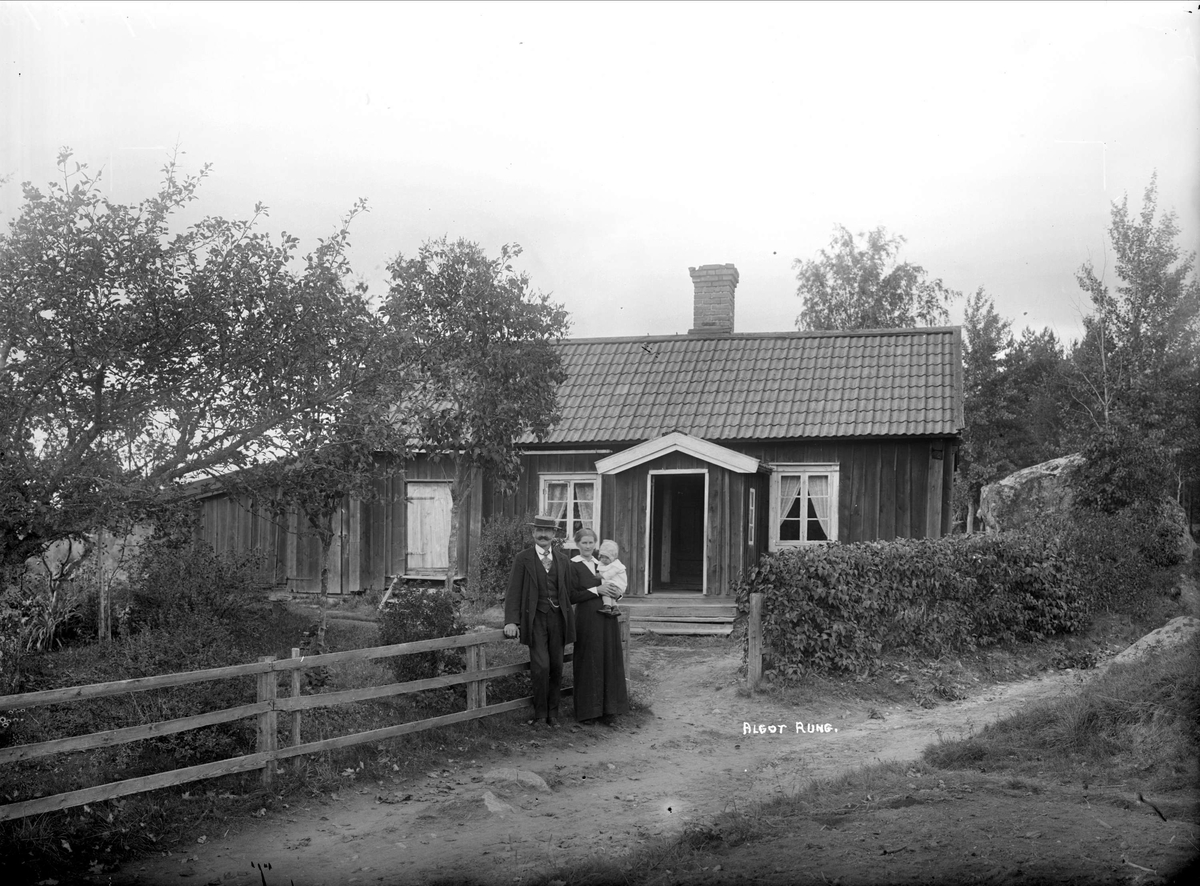 Algot Rung med kvinna och barn framför bostadshus, Uppland 1917