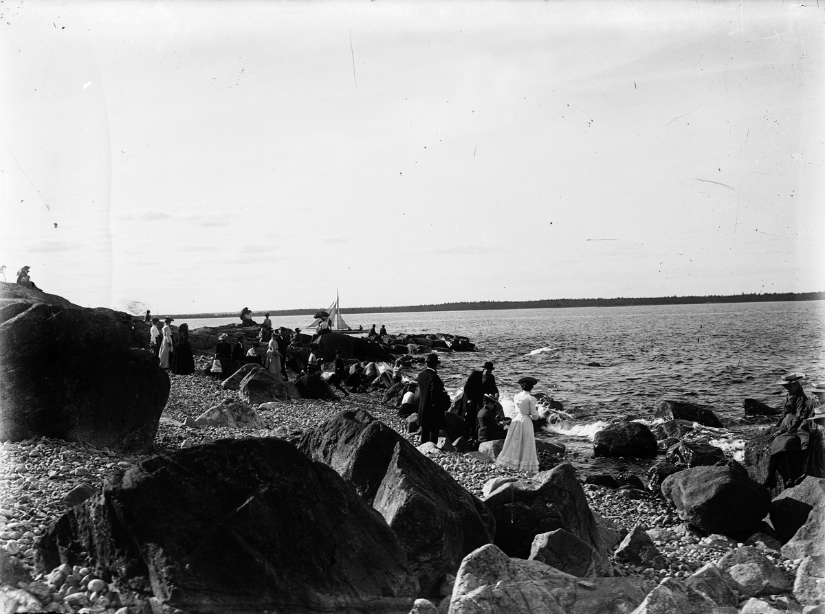 Människor på utflykt vid Furuviks klippiga strand.