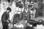 Interiör av fabriksbyggnaden, 6 april 1946. År 1931 inköpte O. M. Grudén av Åbyfors bruk en fabriksbyggnad, där han efter omfattande restaurerings- och moderniserings arbeten  var fabriken klar för att börja användas.  Ingenjör O. M. Grudén grundade fabriken belägen i Åby, Valbo tillverkning av snökedjor. . Kedjorna tillverkas i alla förekommande storlekar och för alla hjuldimensioner för såväl person-som lastautomobiler samt för motorcyklar och traktorer. Sammansättningen av länkarna och kedjorna sker för hand. Omnämnas bör att en man sammansätter 100 kedjor på en dag.