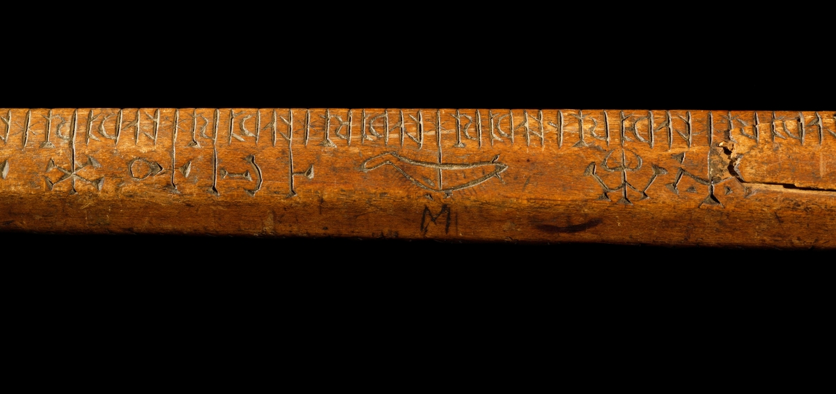 Kalenderstav i form av åttkantig, stavformad runkalender. 
Det korta handtaget har en balusterformigt utförande, med vertikala spetsar runt tvärgående band. Initialer: L P S och inskriptionen 1634 under handtaget och svagt på stavens ände.

S:t Peders lek (med korrektur). En gammal utslagningslek som går ut på att skilja vänner från fiender. Med hjälp av stavens markeringar kunde lekledaren i hemlighet räkna ut vilka personer som skulle slås ut. Namnet syftar på aposteln Petrus roll som himmelrikets portvakt, där han skiljer hedningar från kristna.