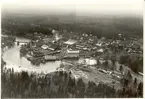 Flygfoto över Blomstermåla möbelfabrik vid en fors i Alsterån. Även brädgårdar och bostadshus finns med.