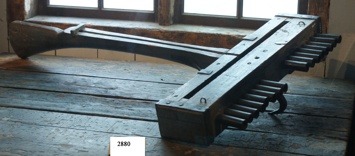 Skottbalk (orgelbössa).  Material: Trä med beslag av järn. Vapnet har 16 stycken pipor av järn. Från 1670-talet.