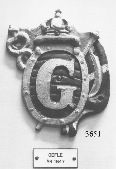 Båtemblem från örlogsfartygens båtar Gefle. Tillkomna år 1930 och 1936.
Äldre nummer K506:38. Metall. Ovalt "G" inom sköld. Röd och guldkrona upptill. På högra sidan: svensk flagg. Gävle. Korvetten Gefle byggt på ÖVK 1847.