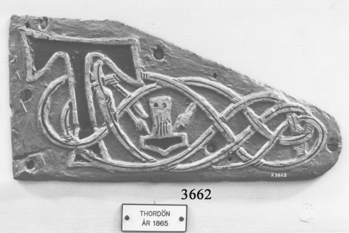 Namnplåt från örlogsfartygens båtar Thordön. Tillkomna år 1930 och 1936.
Äldre nummer K506:11. Matrial av tenn, triangulärt. Blått "T" och Torhammare omgivet av drakslingor.